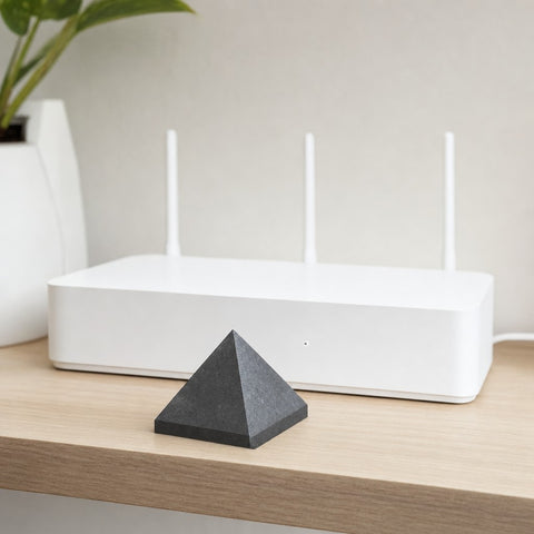EMF Protection Pyramid in front of a home wifi router, showing its 6 cm size