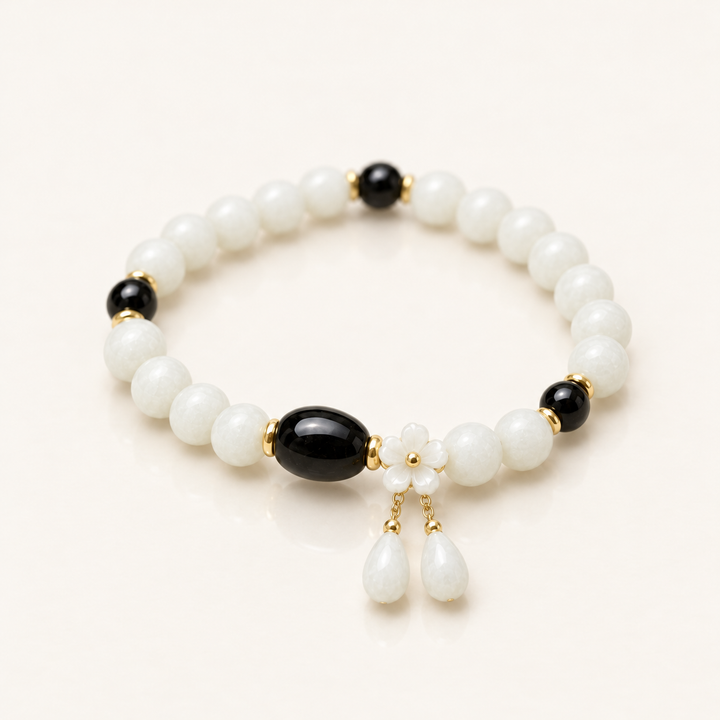 White Jade Guardian Bracelet, angled studio view showing white jade beads, black tourmaline beads and the white flower charm with two drops
